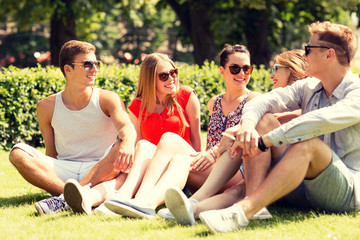 group of smiling friends outdoors sitting on grass