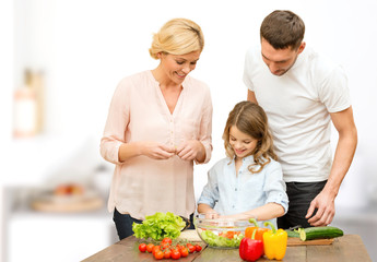happy family cooking vegetable salad for dinner