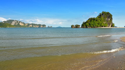Famous limestone cliffs of Krabi bay overlooking wide sandy beach off west coast of Thailand