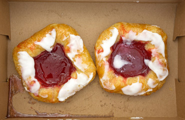 Two raspberry danish in cardboard box