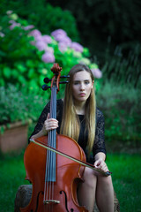 Beautiful blonde girl playing cello in black dress