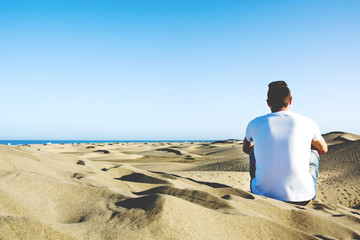 Fototapeta na wymiar Young man sitting on a dune
