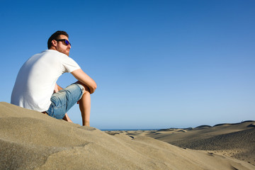 Naklejka na ściany i meble Young man sitting on a dune
