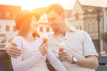 Happiness couple with ice cream sitting at street under sunlight