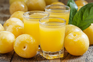 Fototapeta na wymiar Delicious fresh juice of yellow sweet plums in a glass on the ol