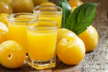 Delicious fresh juice of yellow sweet plums in a glass on the ol