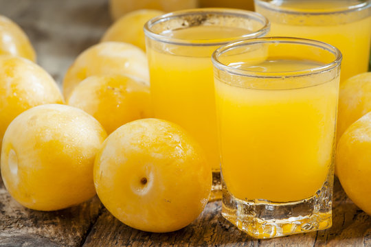 Delicious fresh juice of yellow sweet plums in a glass on the ol