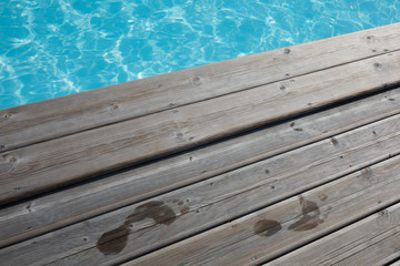 Wet human footprints on dark wooden plank floor
