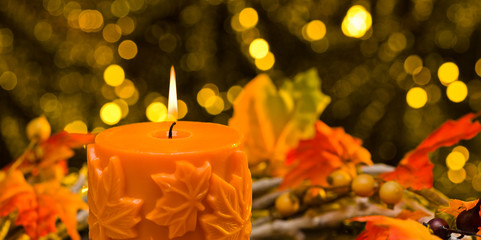 Orange candle in autumn Christmas setting