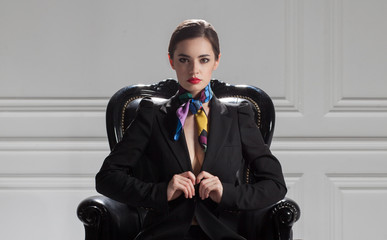 front view of strict business woman in black suit sitting in boss chair