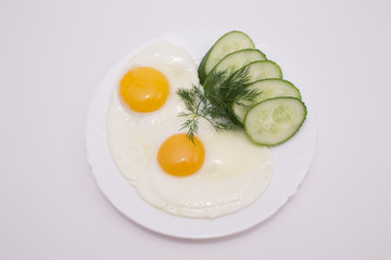Яичница в тарелке с огурцом.