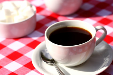 Coffee outdoor.
Cup of coffee outdoors on a gingham tablecloth.