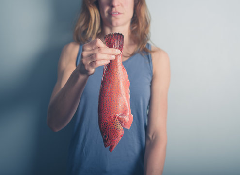 Young woman holding red fish