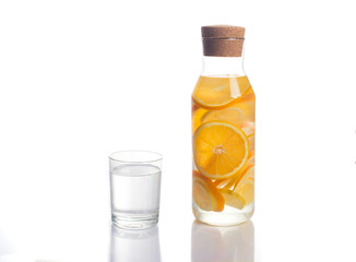 orange and lemon infused water in a glass decanter with a glass 