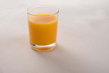 orange juice in a glass on beige fabric background 