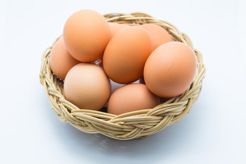 Chicken eggs in a basket on white