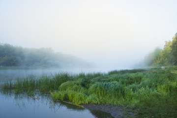 Summer sunrise over the river with a fog