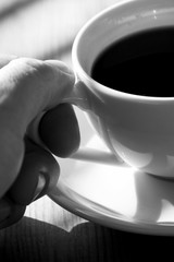 Drinking coffee.
Black and white photo of a man drinking a cup of coffee.