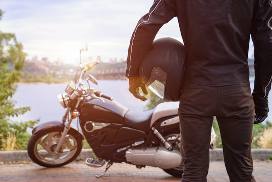 Fototapeta Biker holding helmet with motorcycle on sunset.