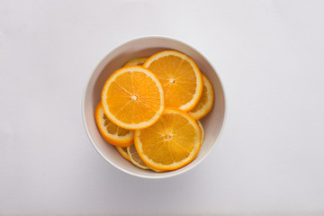 orange slices in a white bowl on white background 