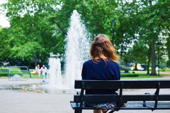 Young woman looking at fountain in park