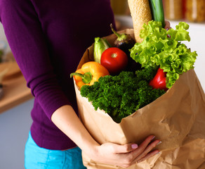 Assorted fruits and vegetables in brown grocery bag holding a