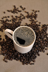 White ceramic coffee mug with coffee beans on cloth sack