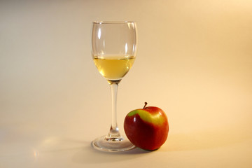 The glass of the white wine and the red apple