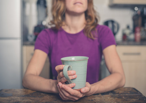 Young woman with cup in kitchen