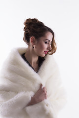Young woman in fur coat on a white background