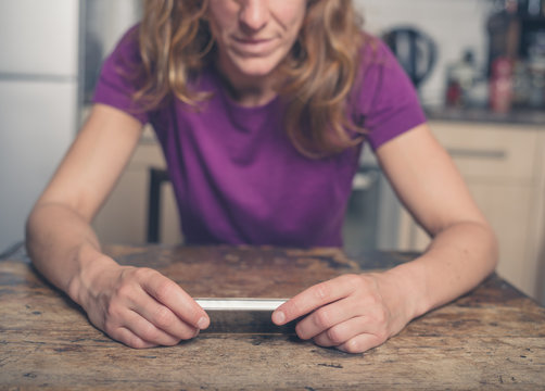 Young woman using smart phone in kitchen