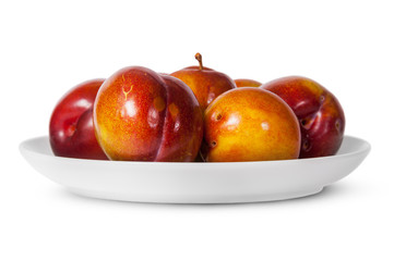 In front red and yellow plums on white plate