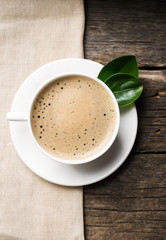 Close-up of coffee cup with roasted coffee beans on wooden background.