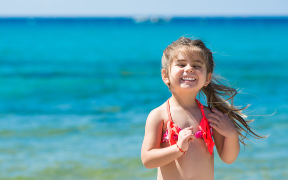 Happy smiling little girl on beach vacation, blu sea background
