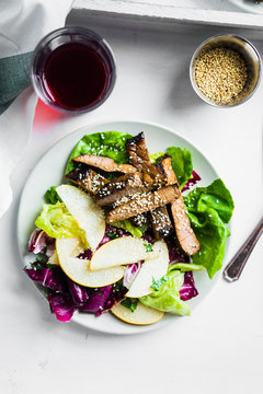Sliced meat steak with green salad and pears