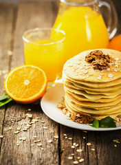 delicious pancakes on wooden table with orange and orange juice