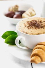 Hot cappuccino and pastries on white wooden boards