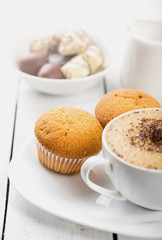 Hot cappuccino and pastries on white wooden boards