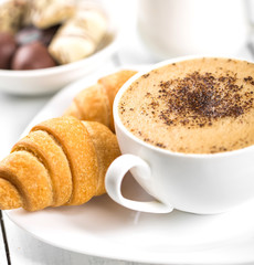 Hot cappuccino and pastries on white wooden boards