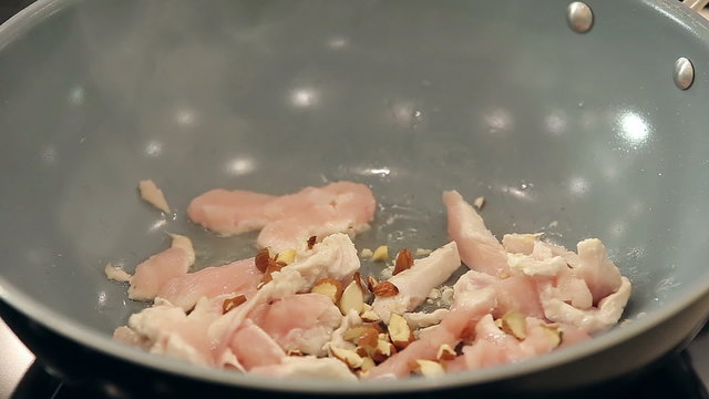 Chef is Putting Sunflower Seeds and Crushed Almonds into Hot Frying Pan with Chicken Fillet