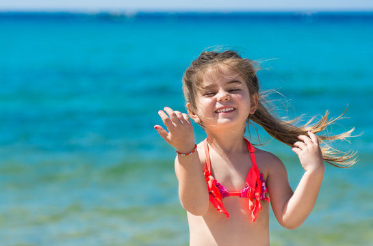 Happy smiling little girl on beach vacation, blu sea background
