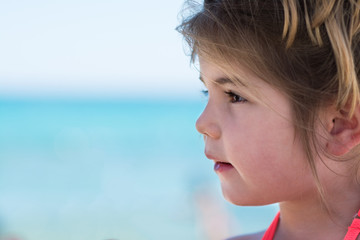 Happy cute little girl on beach vacation, blu sea background