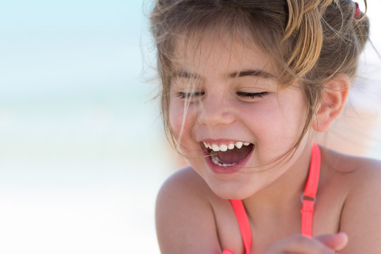 Happy smiling little girl on beach vacation, blu sea background