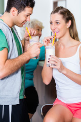 Frau und Mann trinken Proteinshake im Fintessstudio