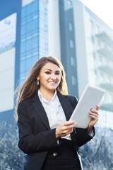 Successful businesswoman or entrepreneur using a digital tablet computer, standing in front of his office.