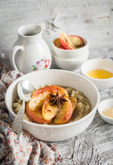 oatmeal with caramelized apples and cinnamon in a white bowl on a light wooden background - healthy Breakfast