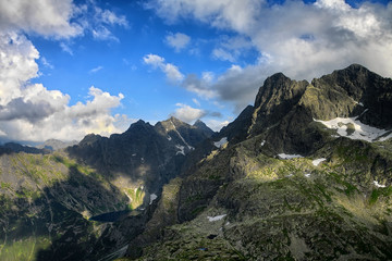 Lake hidden high in mountain in stunning patches of shadows and light 