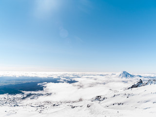 Mount Ngauruhoe poking through clouds from slopes of Mt Ruapehu and Tongariro in distance.