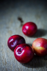 Juicy plums in old wooden tray on black background