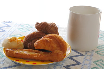 Breakfast of milk and mini bread. Croissant, chocolate croissant, banana bread and green soybean bread.